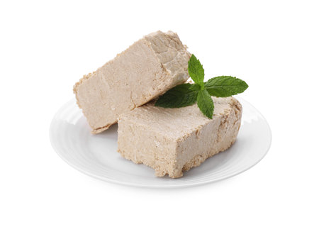 Plate with pieces of tasty halva and mint isolated on whiteの写真素材