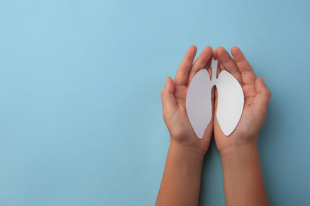 Child holding paper human lungs on light blue background, top view. Space for textの写真素材