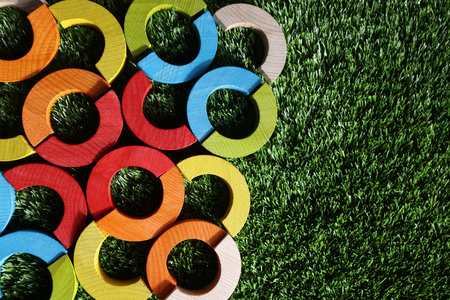 Colorful wooden pieces of play set on green grass, top view with space for text. Educational toy for motor skills developmentの写真素材
