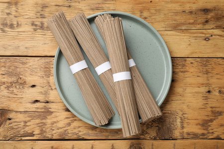 Uncooked buckwheat noodles (soba) on wooden table, top view