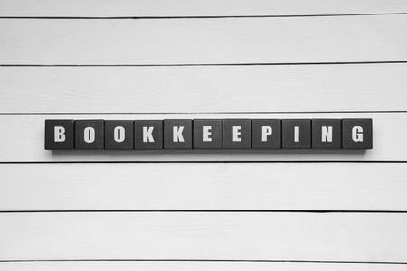Word Bookkeeping made with black cubes on white wooden table, top viewの写真素材