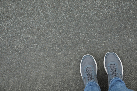 Man in sneakers standing on asphalt, top view. Space for textの写真素材