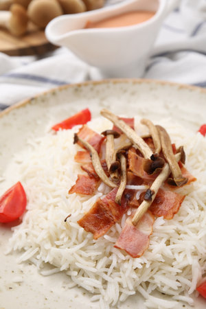 Delicious rice with bacon, mushrooms and tomatoes on plate, closeupの写真素材