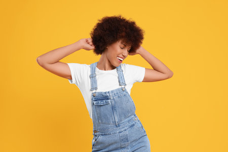 Happy young woman dancing on orange backgroundの写真素材