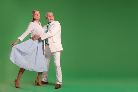 Senior couple dancing together on green background, space for textの写真素材