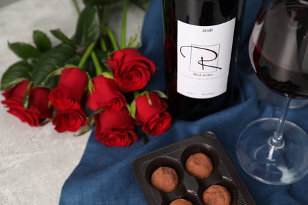 Red wine, chocolate truffles and roses on light textured table, closeupの写真素材
