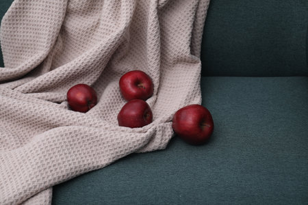 Red apples and beige blanket on green sofaの写真素材