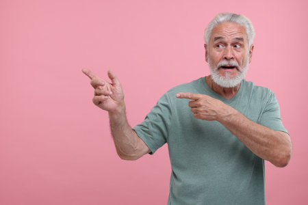 Special promotion. Senior man pointing at something on pink background. Space for textの写真素材