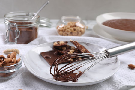 Whisk with chocolate cream and ingredients on tableの写真素材