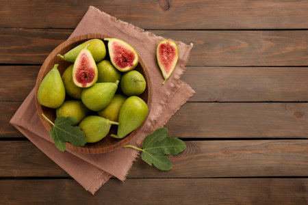 Cut and whole green figs on wooden table, flat lay. Space for textの写真素材