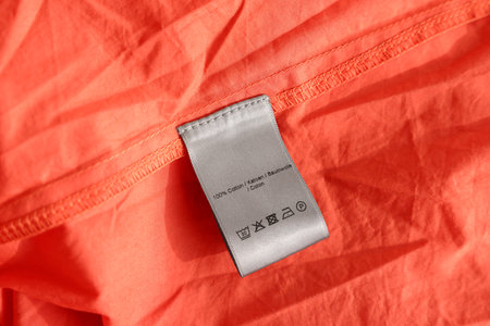 Clothing label in different languages on orange garment, closeupの写真素材