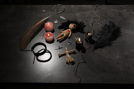 Female voodoo doll with pin in heart and ceremonial items on gray tableの写真素材