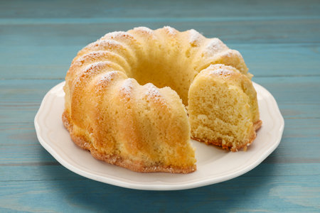 Delicious freshly baked sponge cake on light blue wooden table, closeup