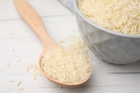 Spoon and bowl with raw rice on white wooden table, closeupの写真素材