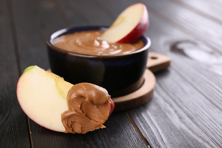Slices of fresh apple with peanut butter on wooden table, closeup. Space for textの写真素材