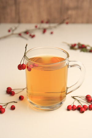 Cup with hawthorn tea and berries on beige table, closeupの写真素材