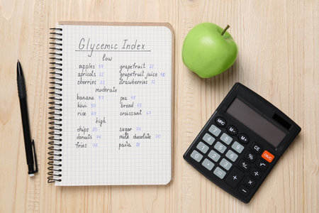 Notebook with products of low, moderate and high glycemic index, pen, calculator and apple on wooden table, flat layの写真素材