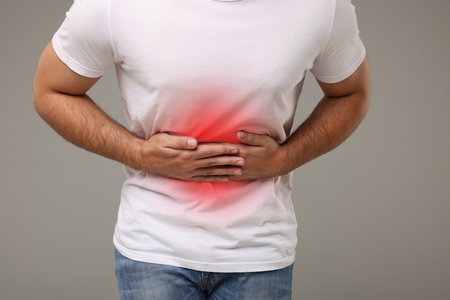 Man suffering from stomach pain on gray background, closeupの写真素材