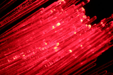Optical fiber strands transmitting red light in darkness, macro viewの写真素材