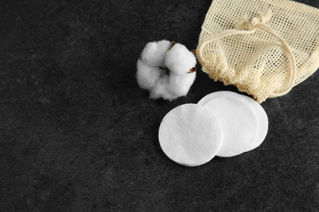 Cotton pads, bag and flower on black table, above view. Space for textの写真素材