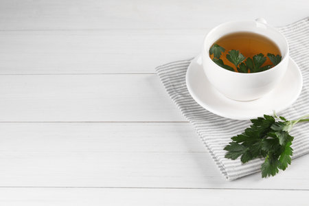 Aromatic herbal tea and fresh parsley on white wooden table, space for textの写真素材