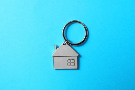 Metallic keychain in shape of house on light blue background, top viewの写真素材