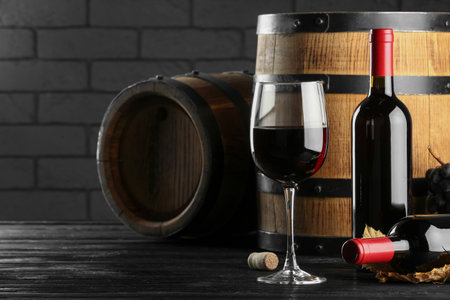 Delicious wine and wooden barrels on black table, space for textの写真素材
