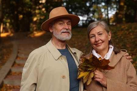 Portrait of affectionate senior couple with dry leaves in autumn parkの写真素材