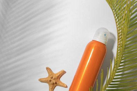 Sunscreen, starfish and tropical leaf on white background, flat lay and space for text. Sun...