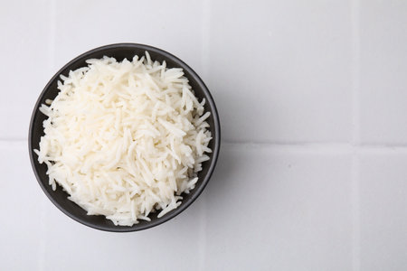 Bowl of delicious rice on white table, top view. Space for textの写真素材