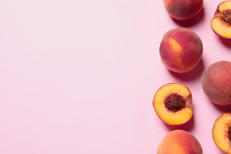 Cut and whole fresh ripe peaches on pink background, flat lay. Space for text