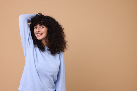 Happy young woman in stylish light blue sweater on beige background, space for textの写真素材