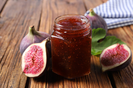 Jar of tasty sweet jam and fresh figs on wooden table, closeupの写真素材