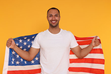 4th of July - Independence Day of USA. Happy man with American flag on yellow backgroundの写真素材