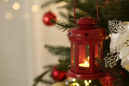 Christmas lantern with burning candle on fir tree indoors, closeup. Space for textの写真素材