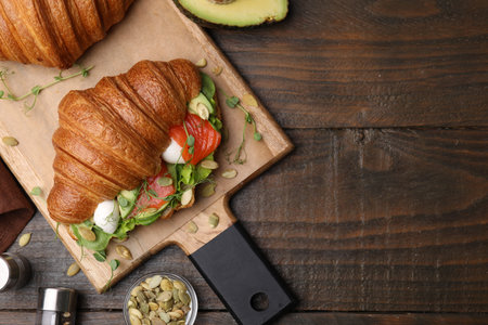 Tasty croissant with salmon, avocado, mozzarella and lettuce served on wooden table, flat lay. Space for textの写真素材