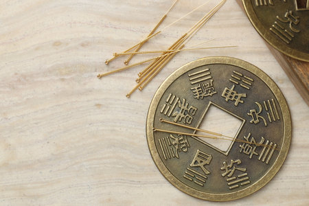 Acupuncture needles and ancient coin on beige marble table, flat lay. Space for textの写真素材