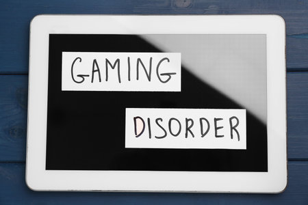 Tablet with phrase Gaming Disorder on blue wooden table, top view. Addictive behaviorの写真素材