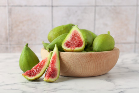Cut and whole green figs on white marble tableの写真素材