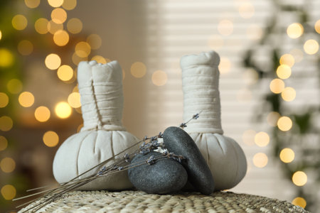 Spa composition. Herbal bags, stones and dry lavender flowers on wicker mat indoors, bokeh effectの写真素材