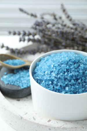Bowl with blue sea salt and lavender flowers on white table, closeup. Space for textの写真素材