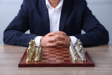 Man with chess pieces on checkerboard at wooden table before game, closeupの写真素材
