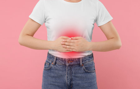 Woman suffering from stomach pain on pink background, closeupの写真素材