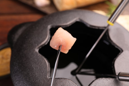 Fork with piece of raw meat over fondue pot, closeupの写真素材