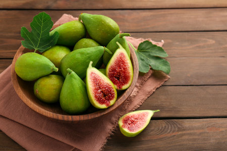 Cut and whole green figs in bowl on wooden table, closeupの写真素材