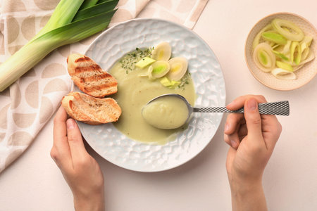 Woman eating delicious leek soup with croutons at light table, top viewの写真素材