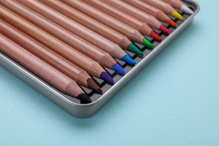 Colorful pastel pencils in box on light blue background, closeup. Drawing suppliesの写真素材