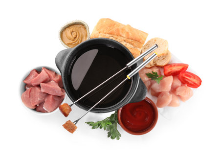 Fondue pot with oil, forks, meat pieces and other products isolated on white, top viewの写真素材