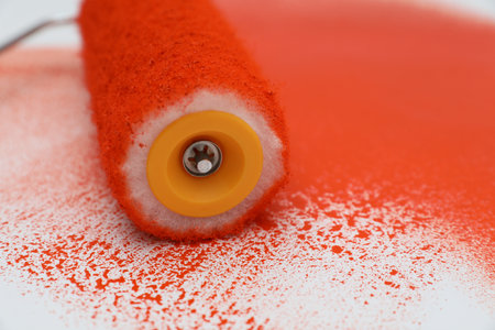 Roller brush and strokes of orange paint on white background, closeupの写真素材