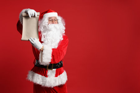 Merry Christmas. Santa Claus showing blank paper sheet on red background, space for textの写真素材